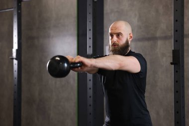 Sporcu jimnastik yaparken kettlebell salıncak yapıyor.