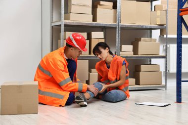 İşte bir kaza oldu. Depoda yaralı meslektaşına yardım eden adam.