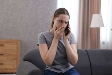 Depresyondaki kadın evdeki kanepede ruh sağlığı için yardım hattını arıyor.