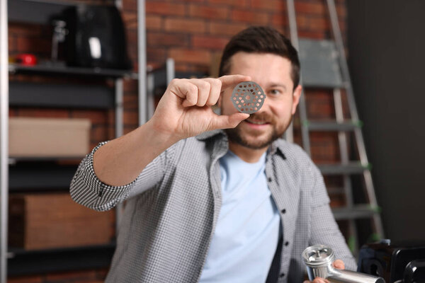 Relaxing hobby. Smiling man with part of electric meat grinder in workshop, selective focus