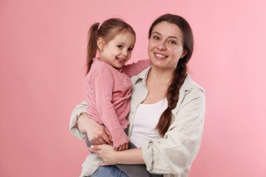 Mutlu anne portresi ve pembe arka planda tatlı kızı.