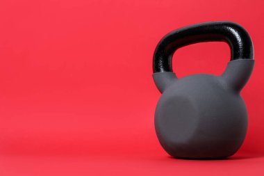 Kırmızı arka planda bir tane kettlebell. Metin için boşluk