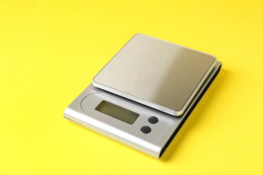 Sarı arka planda modern elektronik mutfak terazisi, yakın plan.