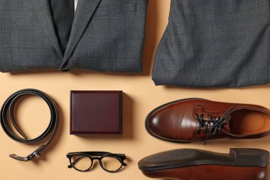 Zarif erkek kıyafeti. Şık takım, aksesuarlar ve bej arka planda ayakkabılar, düz yatış