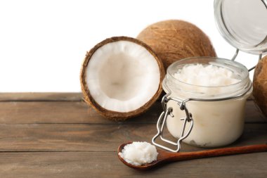 Hindistan cevizleri, pişirme yağı ve kaşık ahşap masada beyaz arka planda