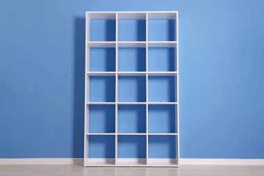 Empty shelving unit near blue wall indoors