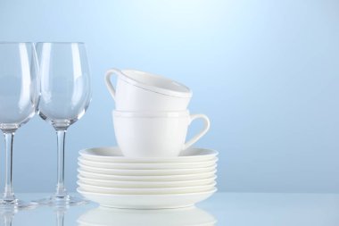 Different clean dishware on light blue background. Space for text