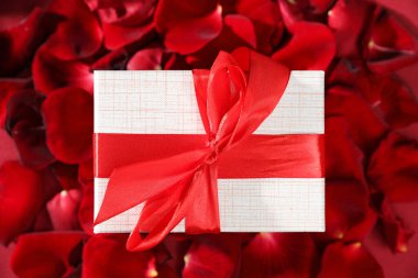 Gül yaprakları arasında güzel bir hediye kutusu, üst manzara. Romantik hediye