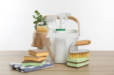 Ahşap masa üzerinde çevre dostu temizlik ürünleri, erzak ve okaliptüs dalları