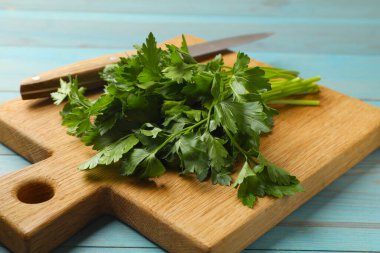 Taze maydanoz ve bıçak açık mavi ahşap masada, yakın plan.