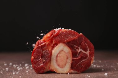 Kahverengi desenli masada siyah arkaplana karşı tuzlanmış çiğ et parçası, yakın plan