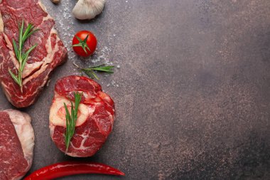 Kahverengi desenli masa üzerinde çiğ sığır eti, baharat ve ürünlerle bezenmiş düz bir kompozisyon. Metin için boşluk