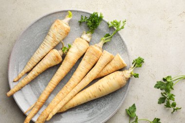 Gri masada taze maydanoz ve kökler, üst manzara.