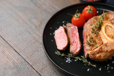 Lezzetli et parçaları, ahşap masada baharatlar ve domatesler, yakın plan. Metin için boşluk
