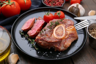 Lezzetli et parçaları, ahşap masada baharatlar ve domatesler, yakın plan.