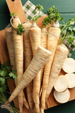 Yeşil ahşap masa üzerinde maydanoz kökleri ve yapraklar, üst manzara