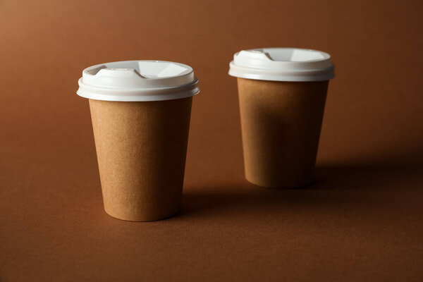 Paper cups with lids on brown background. Mockup for design