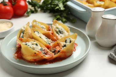 Beyaz masada servis edilen ricotta ve ıspanakla doldurulmuş lezzetli kabuklu makarna.
