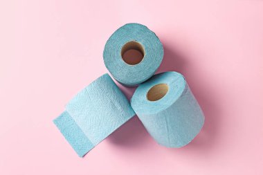 Açık pembe zemin üzerinde mavi tuvalet kağıdı ruloları, üst görünüm