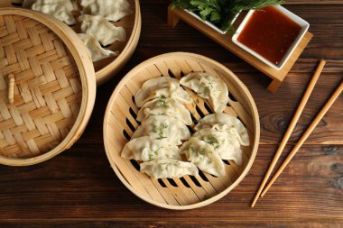 Bambu buharlı buharda kaynamış gyoza (hamur tatlısı), sos ve çubuklar ahşap masada, düz yerde.