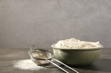 Kahverengi pirinç unu ve elek gri masada. Metin için boşluk