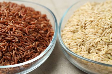 Açık gri masada cam kaselerde farklı tipte kahverengi pirinç, yakın plan.