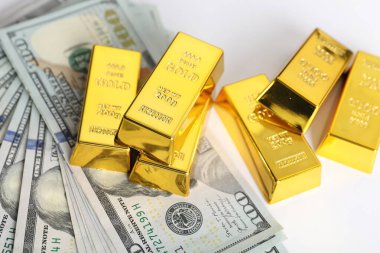 Parlak altın külçeler ve beyaz arka planda dolar banknotları, yakın plan