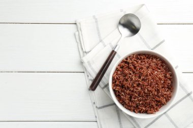 Lezzetli kahverengi pirinç kasede ve kaşıkla beyaz ahşap masa, üst manzara. Metin için boşluk