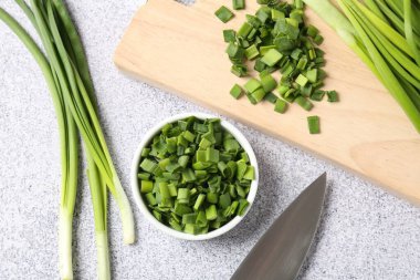 Taze yeşil soğan ve bıçak açık gri masada, düz yatıyordu.