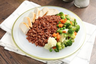 Tahta masada servis edilen tavuk ve sebzeli lezzetli kahverengi pirinç.