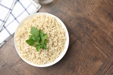 Ahşap masada servis edilen maydanozlu lezzetli kahverengi pirinç, üst manzara. Metin için boşluk