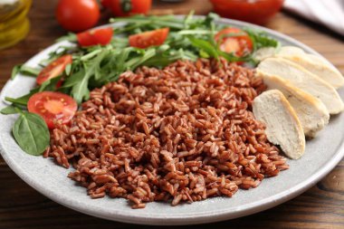 Tahta masada servis edilen tavuk ve salatalı leziz kahverengi pirinç, yakın plan.