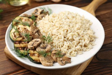 Mantarlı ve dereotlu lezzetli kahverengi pirinç ahşap masada servis edilir.