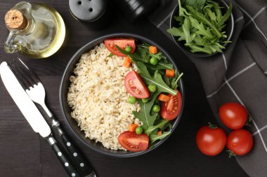 Siyah ahşap masada servis edilen sebzeli lezzetli kahverengi pirinç.