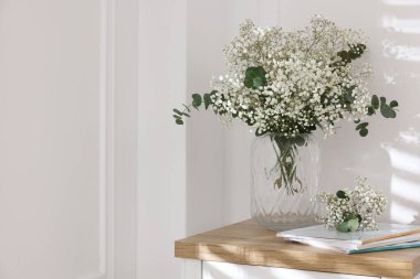 Evdeki masasında okaliptüs dalları vazoda ve dergiler olan güzel gypila çiçekleri. Metin için boşluk