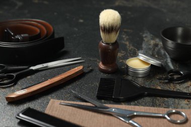 Many different barber's tools on black textured table, closeup
