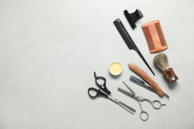 Many different barber's tools on light grey table, flat lay. Space for text