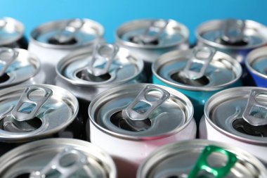 Açık mavi arka planda birçok alüminyum içecek kutusu, yakın plan