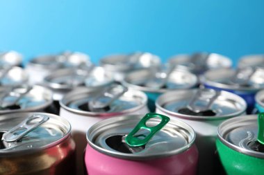 Açık mavi arka planda birçok alüminyum içecek kutusu, yakın plan