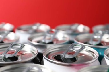 Kırmızı arka planda birçok alüminyum içecek kutusu, yakın plan