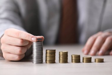 Beyaz ahşap masadaki bozuklukların üzerine para koyan adam, yakın plan.