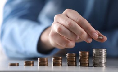 Adam açık gri masadaki bozuklukların üzerine para koyuyor, yakın plan.