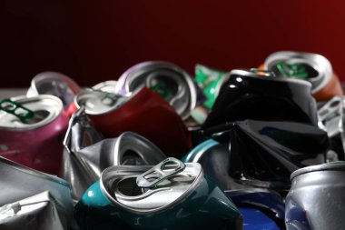 Kırmızı arka planda birçok buruşuk teneke kutu, yakın plan