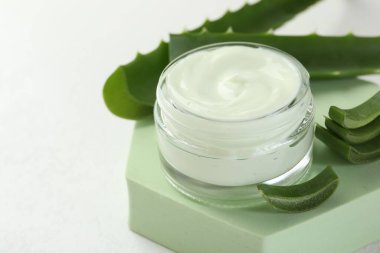 Aloe vera özütüyle nemlendirici krem, beyaz arka planda yapraklar ve podyum, yakın plan. Metin için boşluk