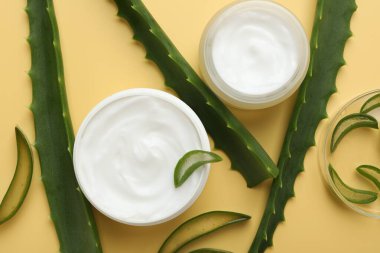 Aloe vera özütüyle nemlendirici krem ve sarı arka planda yapraklar.