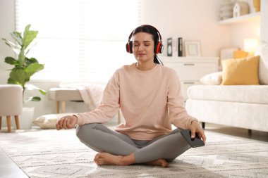 Akıllı telefonlu bir kadın evde meditasyon yapıyor.