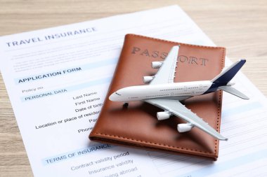 Tıbbi turizm. Seyahat sigortası formu, pasaport ve uçak modeli hafif ahşap arka plan, yakın plan.