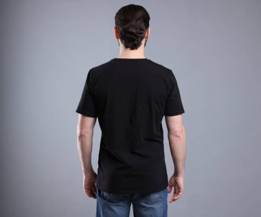 Açık gri arka planda siyah tişört giyen bir adam. Tasarım için model