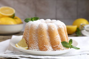 Pudra şekerli lezzetli limonlu pasta, taze meyve dilimi ve ahşap masada nane, yakın plan.