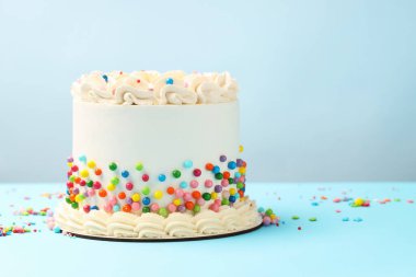 Açık mavi masaya renkli şekerlemeler serpiştirilmiş nefis bento keki, metin için yer.